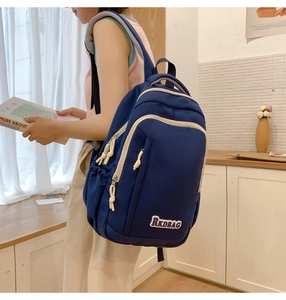 Detailed side view of navy canvas backpack with white contrast zippers on a model