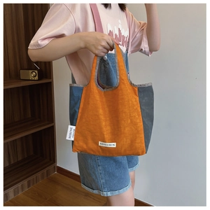 Detail of minimalist tote bag with contrast stitching and branded fabric label accent