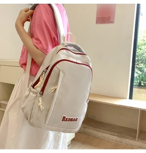 Detail of off-white backpack featuring red zippers and RKDBAG embroidery on bottom