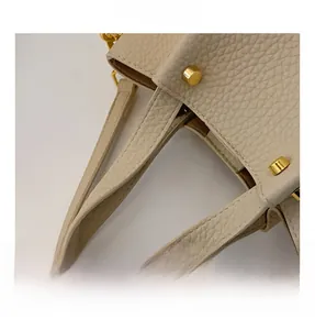 Detailed macro view of the cream leather handbag showing thick handles and gold rivets