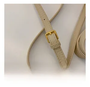 Macro detail of beige pebble leather strap with adjustable gold buckle for shoulder bag