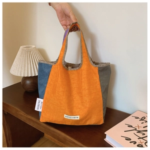 Detail of tricolor stitched tote bag showing fabric texture and MIRFNE woven label