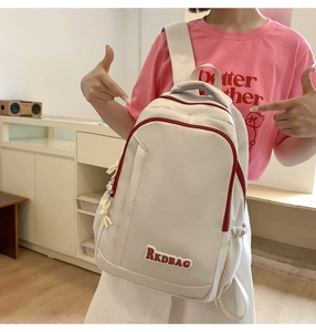 Detail showing off-white nylon backpack with red contrast zippers and RKDBAG letter patch