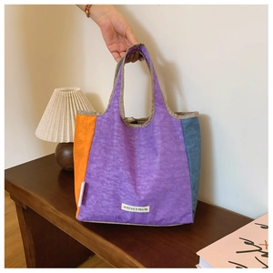 Detail of tricolor patchwork tote bag showing brand logo tag and fabric texture