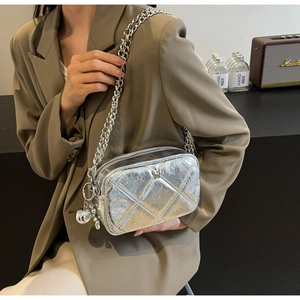 Silver quilted chain bag with metallic finish and sphere charm on stylish model
