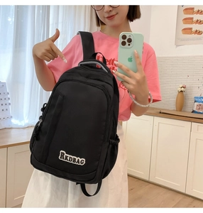 Detail of black nylon backpack featuring white RKDBAG logo and front zipper pocket