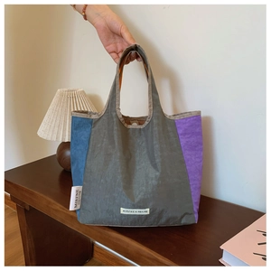 Close-up of color-block canvas tote bag with woven logo on wooden table setting