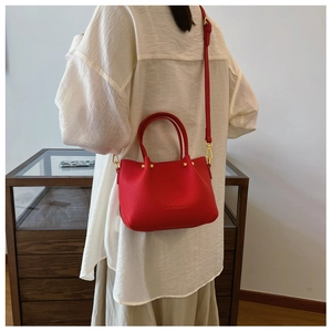 Detailed view of red pebble leather bucket bag with gold hardware and shoulder strap