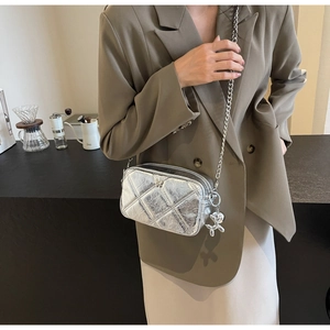 Detail of silver metallic quilted crossbody bag with stylish balloon dog charm