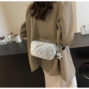 Detail of silver metallic quilted bag with chain strap and balloon dog charm