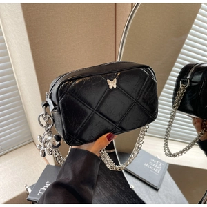 Detail of black quilted leather shoulder bag with silver butterfly and balloon dog charm