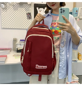 Close-up of red nylon backpack showing functional zipper pockets and side compartments
