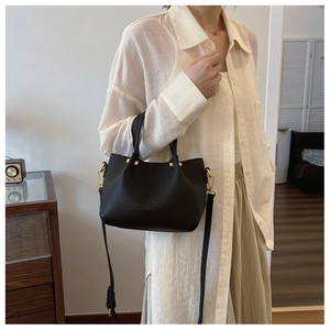 Detail of black lychee grain leather bucket bag with gold hardware and shoulder strap