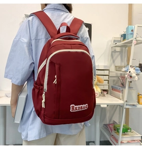 Detail of burgundy large-capacity nylon backpack with RKDBAG patch worn by a student