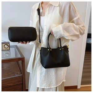Detail of black pebbled leather bucket bag set with gold hardware and shoulder strap