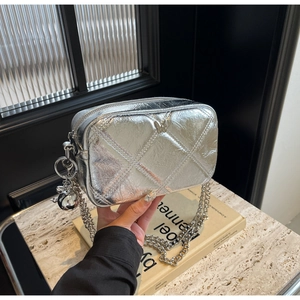 Detail of silver quilted handbag with butterfly buckle and metallic chain strap