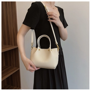Detail of beige pebble leather handbag with gold hardware and brand logo lettering