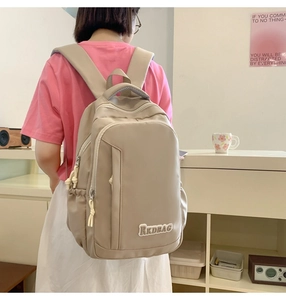 Model wearing a beige nylon backpack with functional pockets and RKDBAG embroidery