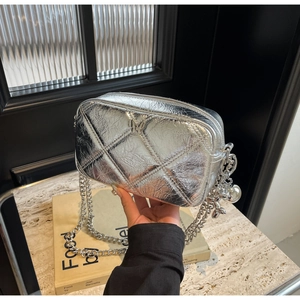 Detail of silver quilted handbag featuring metallic crinkled texture and charm