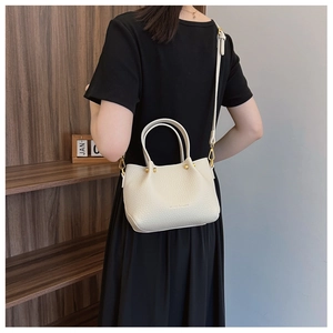 Detail of off-white grain leather bucket bag with gold hardware and slim strap