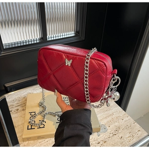 Detail of red quilted chain bag with silver butterfly charm and metallic finish