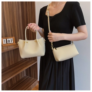 Detail of cream leather bucket bag set with gold chain and metal ball decoration
