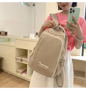 Detail of khaki nylon backpack featuring a front zipper pocket and side water bottle holder