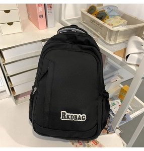 Detail of multi-functional black nylon backpack with branded patch on front pocket