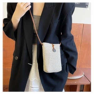 Detail of hand-woven straw mini crossbody bag in beige with brown shoulder strap