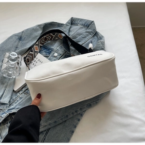 Close-up of white crossbody bag featuring a geometric ethnic style wide strap and logo