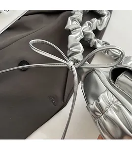 Detail shot of silver metallic pleated bag with bow decoration and ruched shoulder strap