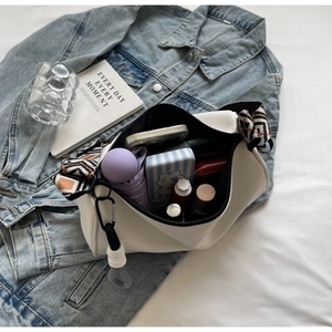 Spacious interior of white crescent crossbody bag with ethnic strap holding daily items