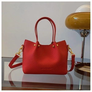 Detail of red lychee pattern leather bucket bag with gold studs and engraved logo