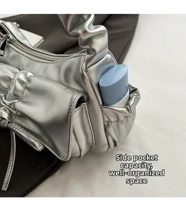 Detail of silver pleated shoulder bag side pocket showing storage space for cosmetics
