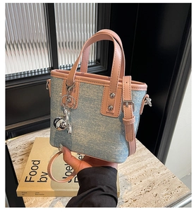 Detail of mini denim bucket bag with pink leather handles and silver rabbit charm