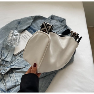 Detail of white cylinder bag with geometric patterned strap and smooth zipper closure