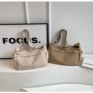 Detail of adjustable wide shoulder strap and dual zipper pockets on large nylon dumpling bag
