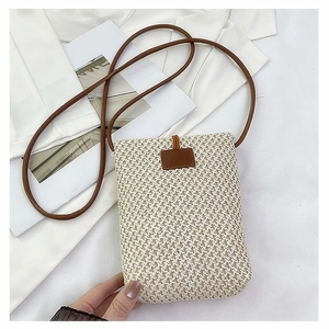 Detail of minimalist straw woven crossbody phone bag with brown leather strap and buckle