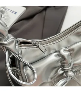 Macro shot of smooth silver zipper and pleated texture on the stylish metallic hobo bag