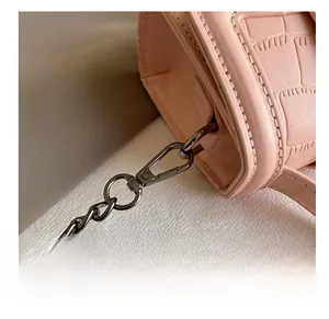 Detail view of pink crocodile pattern leather bag with metallic chain and hook