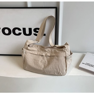Macro detail of beige nylon crossbody bag featuring front zippers and side drawstrings
