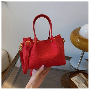 Detail of red lychee grain leather bucket bag with gold hardware and studded accents