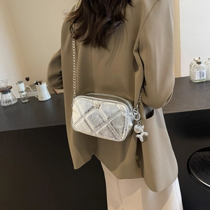 Silver quilted chain bag with balloon dog charm shown as a stylish crossbody shoulder bag