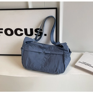 Close-up of fog blue nylon crossbody bag with dual zipper pockets and textured fabric