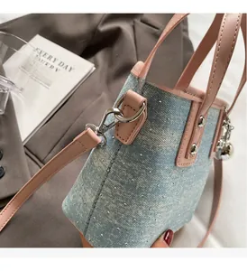 Detail of mini bucket bag with blue denim, silver rhinestones and pink leather strap