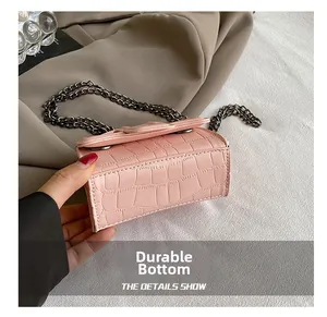 Close-up of light pink croc-embossed mini bag with metal chain and durable bottom