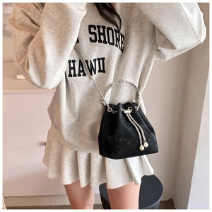 Detail of black bucket bag featuring silver ring handle and pearl drawstring accents