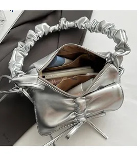 Detailed interior of silver pleated crossbody bag with bow and spacious inner pocket