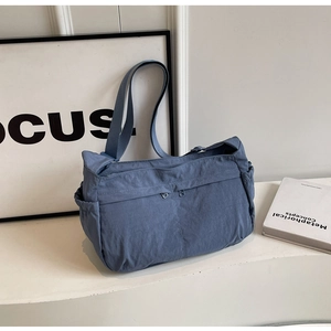 Detail view of grey-blue nylon crossbody bag showing multiple functional zipper pockets