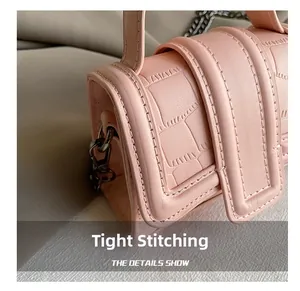 Detail showing tight stitching and crocodile embossed texture on pink mini handbag